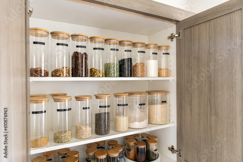 Neatly organized labeled food pantry in a home kitchen with spices grains flour rice sugar nuts