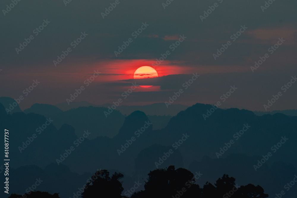 Vibrant sunset from Tiger Cave Temple (Wat Tham Suea) in Krabi, Thailand. Clouds around the sun looking like Saturn