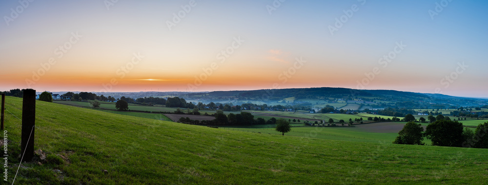 An early morning with a sky full of beautiful colors during sunrise in the rolling hills landscape of Limburg with spectacular views over the typical small villages of this region