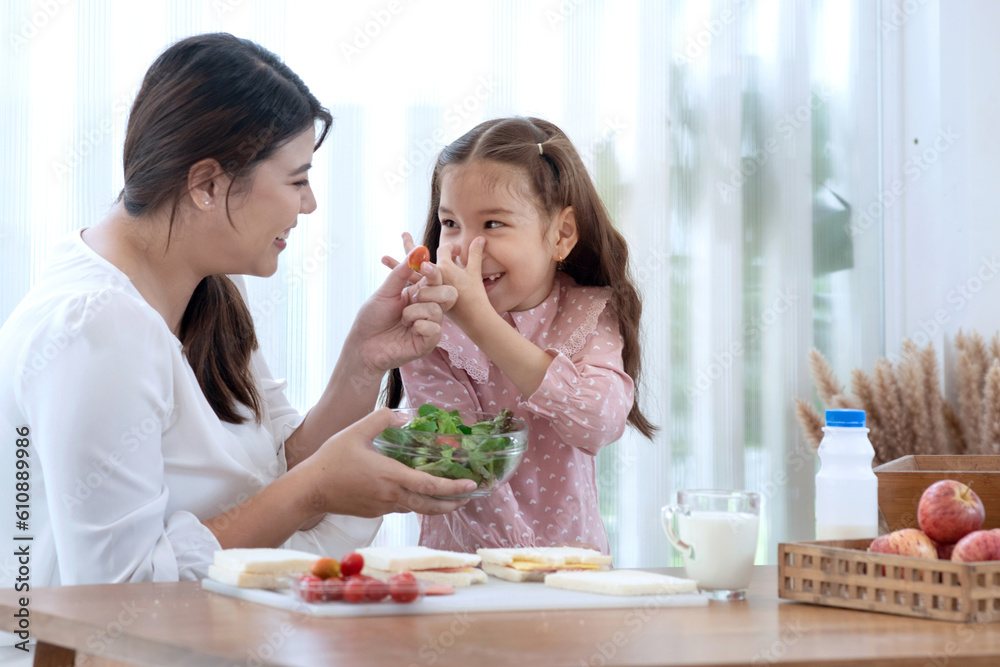 Little girl shows a gesture of covering her nose with her fingers while her mother sent vegetables to try, don't want to eat vegetables Little girl shows a gesture of covering her nose with her fingers while her mother sent vegetables to try, don't want to eat vegetables