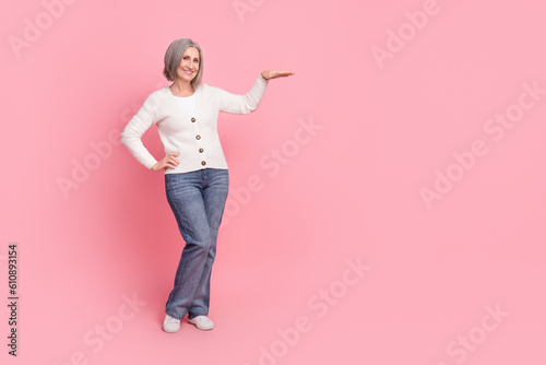 Full length photo of pretty aged person hand measure show empty space proposition isolated on pink color background