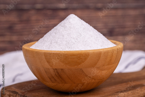 Natural minaret crystal non-iodized grinding salt on wooden background. Ground rock salt in wooden bowl. Close up