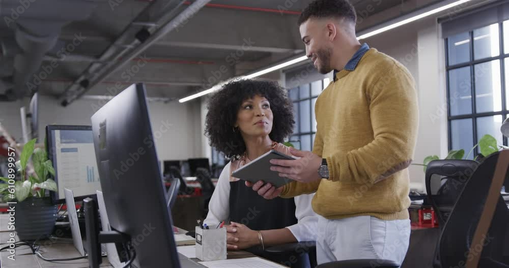 Diverse male and female colleagues looking at tablet, talking and smiling, slow motion Diverse male and female colleagues looking at tablet, talking and smiling, slow motion