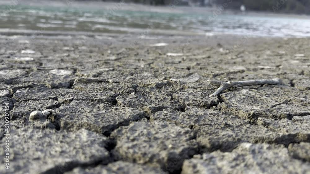 Low shot of The cracked ground contrasts with the abundant water on the shores of the Klöntalersee lake Glarus Kanton, Switzerland Low shot of The cracked ground contrasts with the abundant water on the shores of the Klöntalersee lake Glarus Kanton, Switzerland