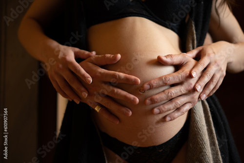 Fotografie detail of the couple's hands resting on her expectant belly