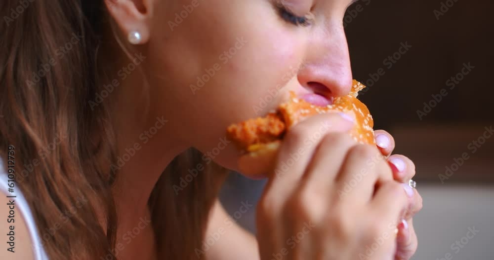 Young woman eating a hamburger - human addiction to unhealthy food. The harmful effects of eating such unhealthy foods, especially for young people. Young woman eating a hamburger - human addiction to unhealthy food. The harmful effects of eating such unhealthy foods, especially for young people.