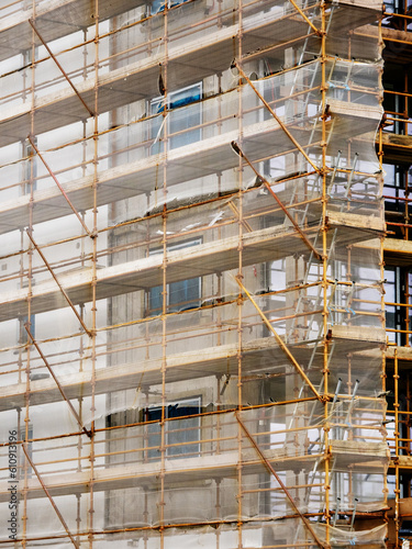 Side of a new building in scaffolding and safety nets. Construction site safety measures. Developing commercial or residential property. Growth concept.