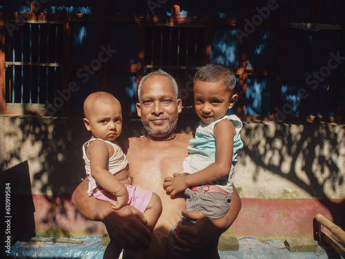 Fotografie South asian rural grandfather holding his two little grandsons