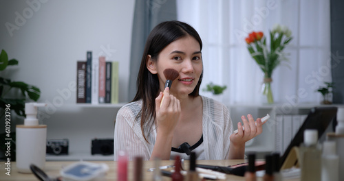 Beautiful young Asian woman blogger shows how to make up and use cosmetics