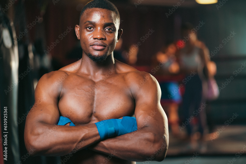 Fototapeta premium Inspirational exercise and fitness portrait of African American male athlete, intense and powerful expression, Young confident boxer muscular man standing in ready stance, boxing ring arena background