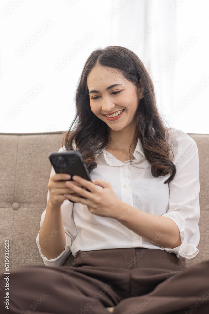 Portrait of a young happy asian female freelancer sitting on the couch and working on project, watching movie on phone laptop, studying, blogging, resting and chatting online. Portrait of a young happy asian female freelancer sitting on the couch and working on project, watching movie on phone laptop, studying, blogging, resting and chatting online.