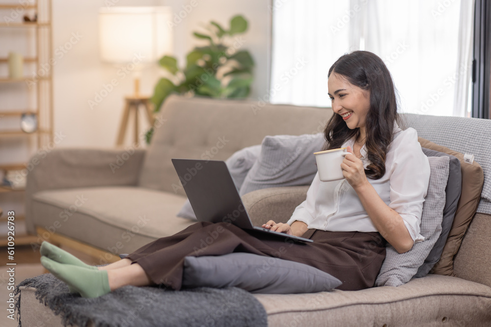 Portrait of a young happy asian female freelancer sitting on the couch and working on project, watching movie on laptop, studying, blogging, resting and chatting online. Portrait of a young happy asian female freelancer sitting on the couch and working on project, watching movie on laptop, studying, blogging, resting and chatting online.