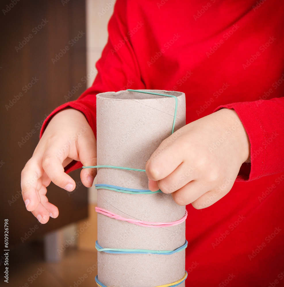 Little boy putting rubber bands or erasers on cardboard roll. Best