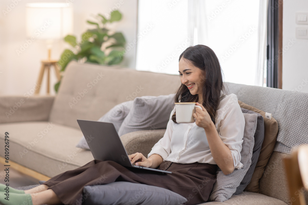 Portrait of a young happy asian female freelancer sitting on the couch and working on project, watching movie on laptop, studying, blogging, resting and chatting online. Portrait of a young happy asian female freelancer sitting on the couch and working on project, watching movie on laptop, studying, blogging, resting and chatting online.