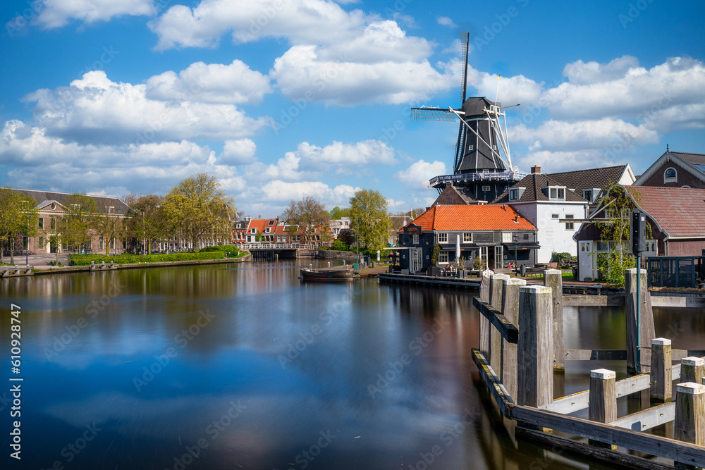 Colorful Romantic View of Harlem Cityscape with Landmark Windmill De Adriaan on Spaarne River at Daytime in Harlem, Netherlands