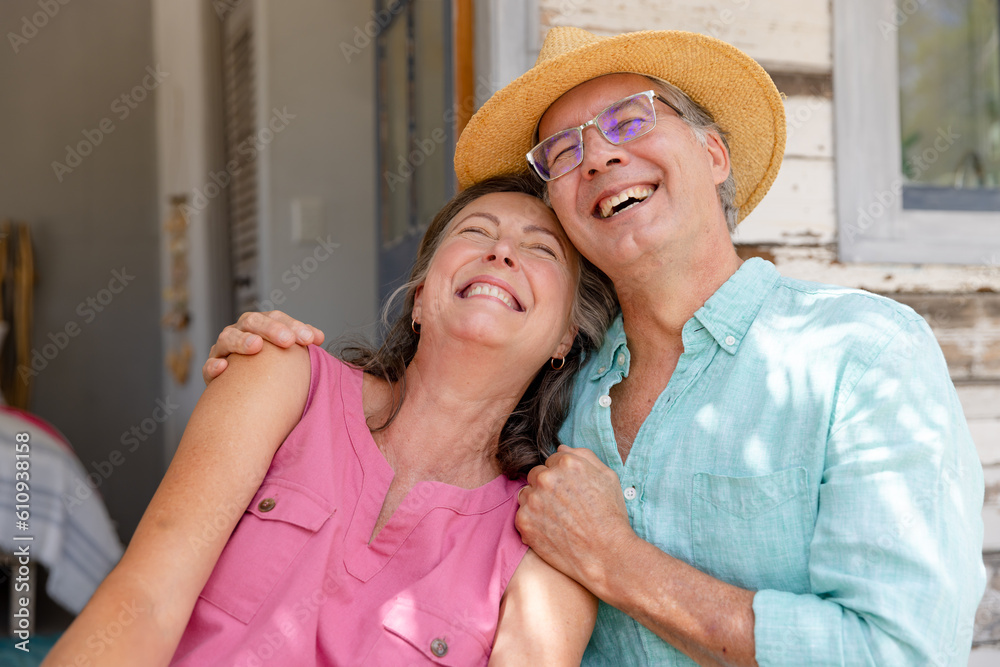 Caucasian senior husband and wife laughing cheerfully while relaxing outside cottage