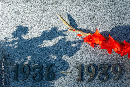 Fechas de la guerra civil española en una placa de mármol con unas flores.