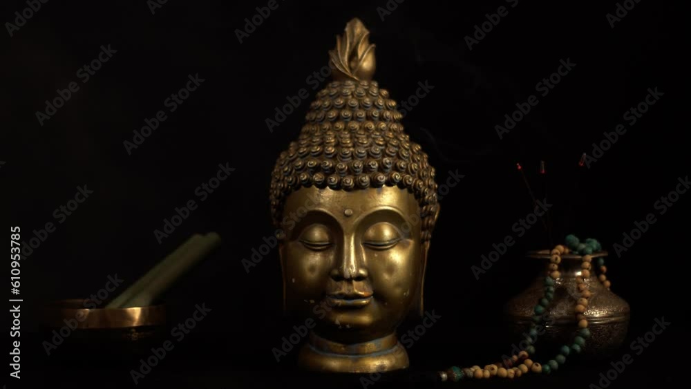 Bronze head of the Buddha with tibetian bowl and burning incense sticks, dark background Bronze head of the Buddha with tibetian bowl and burning incense sticks, dark background
