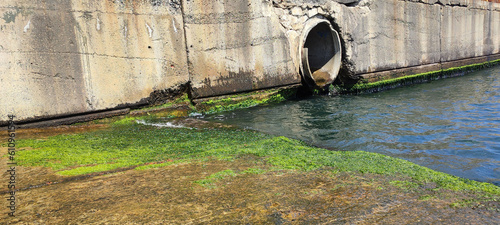 Принти на полотні A large cement drainage system with water flowing out into the sea or a river, c