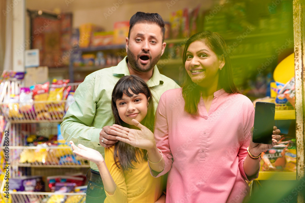 Fototapeta premium Happy family showing empty smartphone Screen at grocery shop.