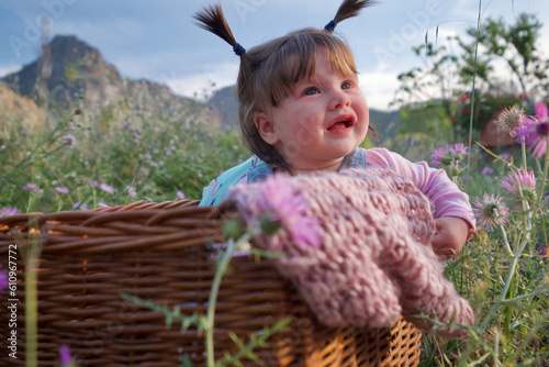 Baby in a basket in the middle of a field of flowers.