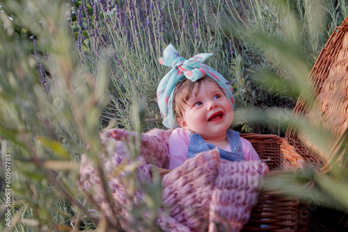 Baby inside a basket smiling in the middle of a lavender garden.
