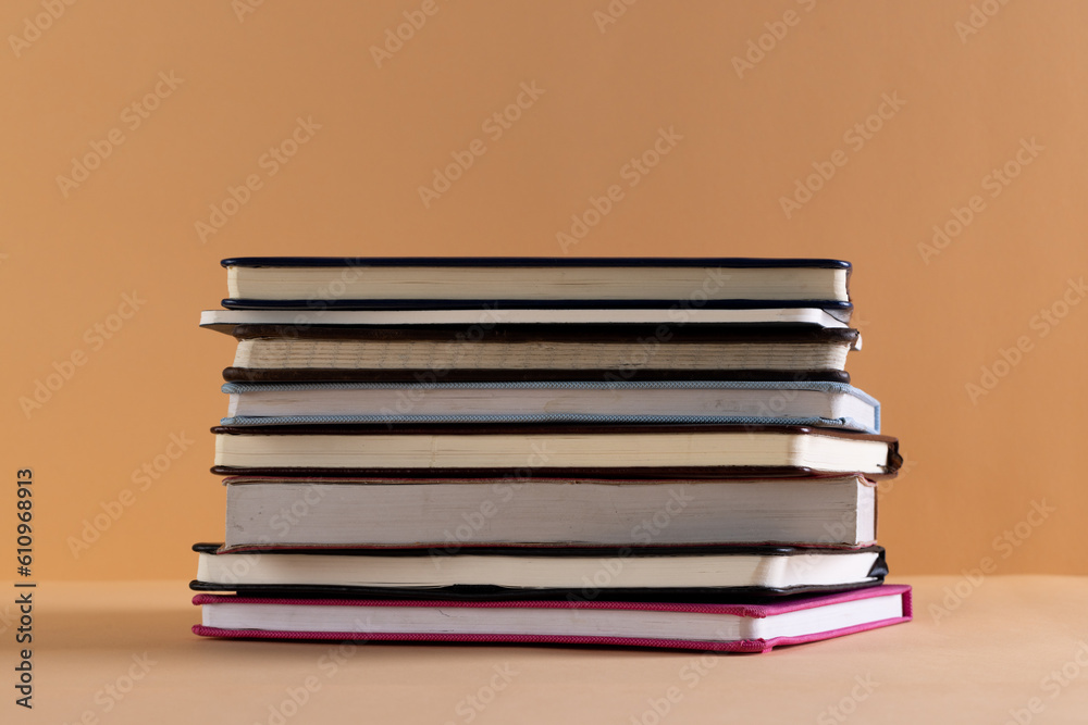 Fototapeta premium Close up of stack of books and notebooks with copy space on orange background
