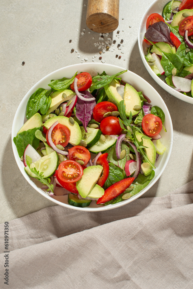 Vegetable salad with tomatoes, avocado and cucumber on a gray background Vegetable salad with tomatoes, avocado and cucumber on a gray background