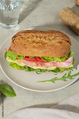 Sandwich with mortadella, cheese and tomatoes on a gray table