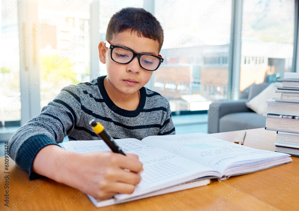 Boy, student and writing in book for studying, homework or learning in education on table at home. Smart little kid or child busy on mathematics, textbooks or problem solving for study in living room Boy, student and writing in book for studying, homework or learning in education on table at home. Smart little kid or child busy on mathematics, textbooks or problem solving for study in living room