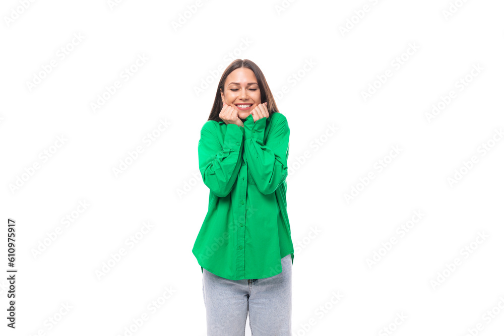 smiling happy young european female model with well-groomed black hair and make-up dressed in a green shirt on a white background with copy space