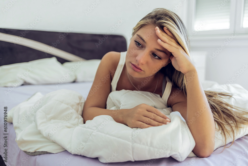 Lonely young Caucasian woman sitting on bed. Depressed hispanic girl at home, looking away with sad expression. Lonely young Caucasian woman sitting on bed. Depressed hispanic girl at home, looking away with sad expression.