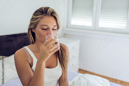 Woman is drinking water at morning. Beautiful woman drinking water in her bedroom.