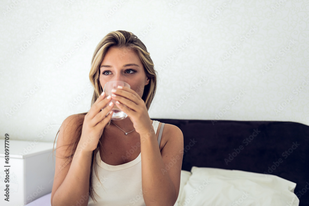 Beautiful young woman holding a glass of water. A young woman drinking a glass of water before bed. Beautiful young woman holding a glass of water. A young woman drinking a glass of water before bed.