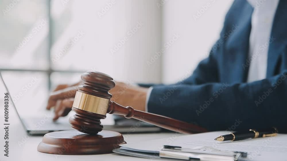 Justice and law concept.Male judge in a courtroom with the gavel, working with, computer and docking keyboard, eyeglasses, on table in morning light Justice and law concept.Male judge in a courtroom with the gavel, working with, computer and docking keyboard, eyeglasses, on table in morning light