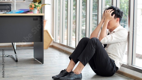 Desperate sad jobless man put head on hands while sitting near large glass window in office. Unsuccessful failed, Stressed after dismissal, Boss and company bankruptcy concept