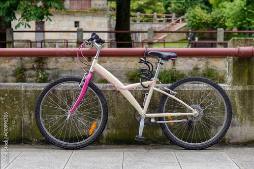 bicycle tied to a pipe near a concrete parapet on a city street