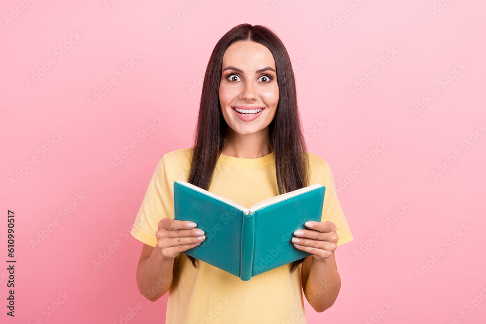 Photo of impressed funky woman dressed yellow t-shirt reading interesting story isolated pink color background Photo of impressed funky woman dressed yellow t-shirt reading interesting story isolated pink color background