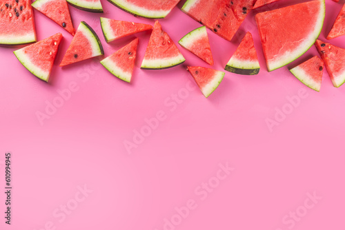 Watermelon slices arranged on high-colored pink background. Simple basic summer harvest and holiday background, top view flat lay banner copy space