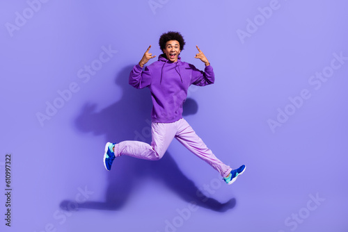 Full size photo of positive crazy person wear stylish pullover jumping showing horns rock symbol isolated on purple color background