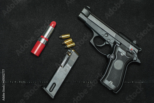 Women's small pistol 9mm and red lipstick on a black sofa.