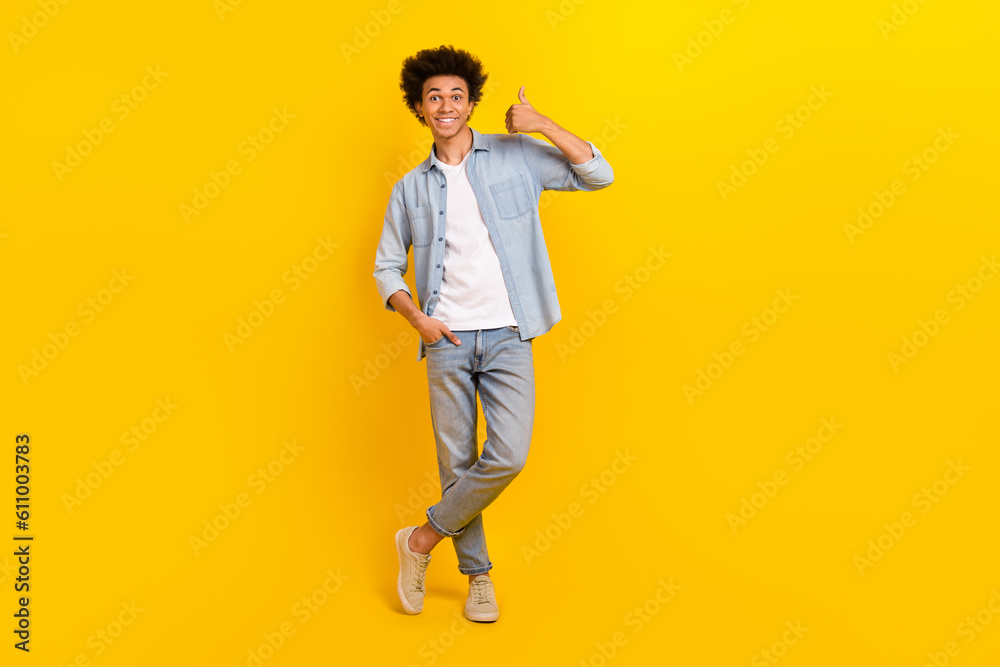 Full length portrait of satisfied person hand finger demonstrate thumb up approval isolated on yellow color background Full length portrait of satisfied person hand finger demonstrate thumb up approval isolated on yellow color background