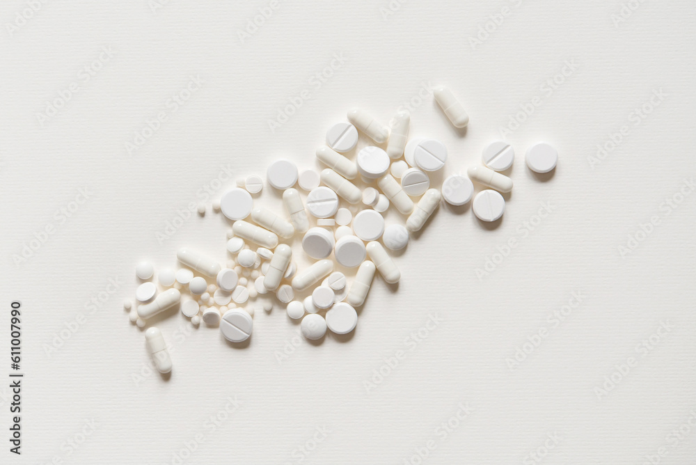 Scattered white pills on a white table. Mock up for special offers as advertising, web background or other ideas. Medical, pharmacy and healthcare concept. copyspace. Empty place for text or logo - obrazy, fototapety, plakaty 