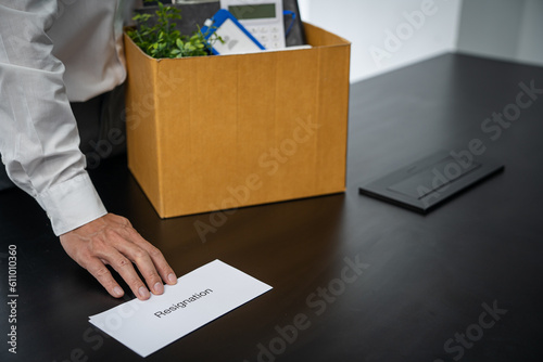 Business man sending resignation letter and packing Stuff Resign Depress or carrying business cardboard box by desk in office. Change of job or fired from company © Charlie's