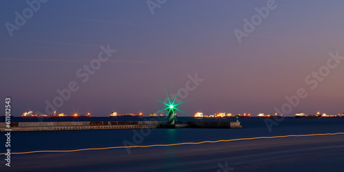 Long exposure photo of green traffic light in the port at night. 