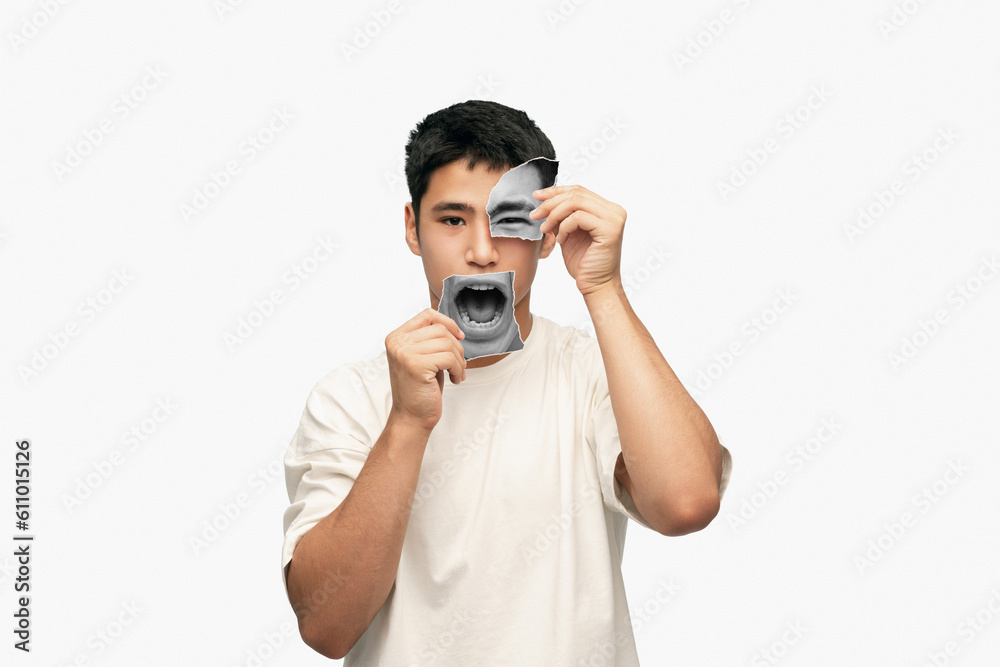 Young asian man with calm face holding photo face parts expressing anger and irritation. Creative collage. Young asian man with calm face holding photo face parts expressing anger and irritation. Creative collage.