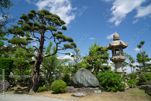 Japanese traditional, historical, beautiful natural garden park with bonsai trees and stone statues in front of blue sky with withe clouds in Suma, Japan