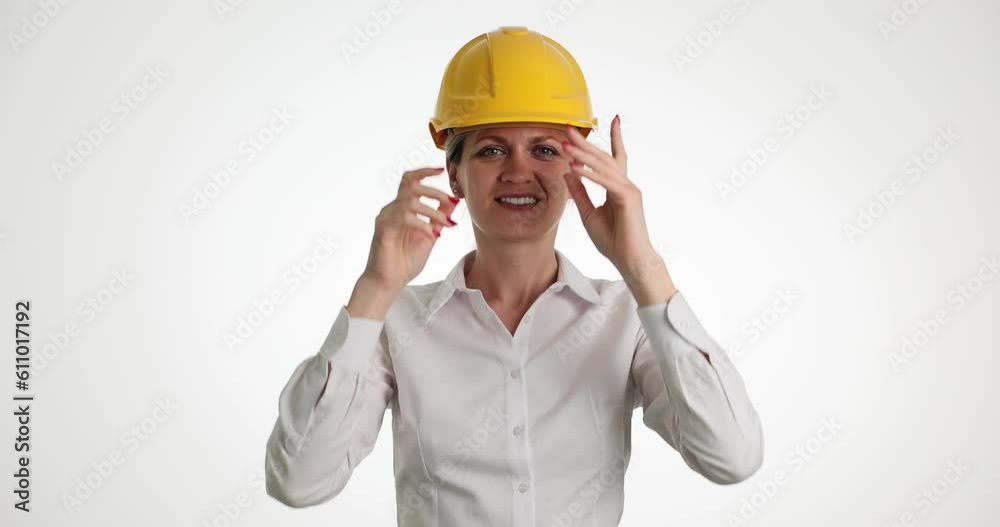 Portrait of woman puts on yellow construction helmet. Woman in construction industry Portrait of woman puts on yellow construction helmet. Woman in construction industry