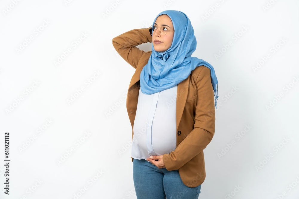 Φωτογραφία Young beautiful pregnant muslim woman wearing hijab over white background confuse and wonder about question