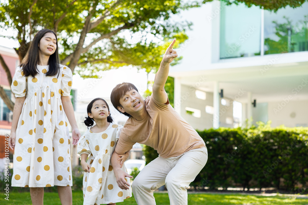 Fototapeta premium asian family Parents and daughters doing a happy walk in the village garden. During the holidays weekends to relax. friendship and living together. member health care. Concept health insurance